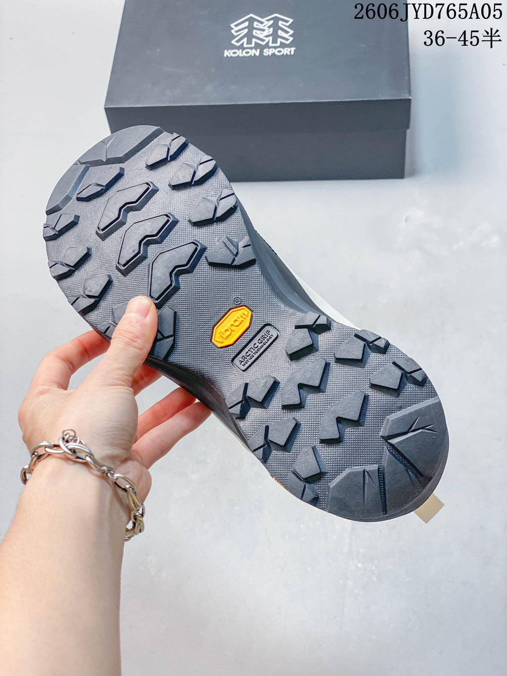 Close-up of the lugged outsole with a visible Vibram logo; Kolon Sport box in background.