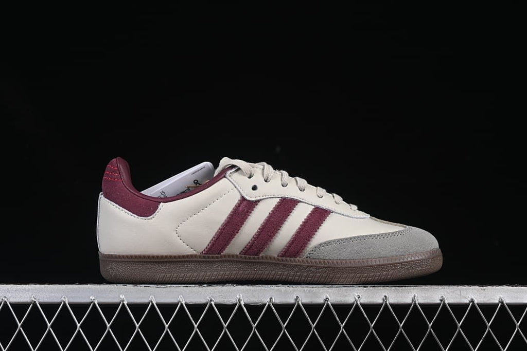 Side profile of the cream sneaker with burgundy stripes and gray toe overlay.