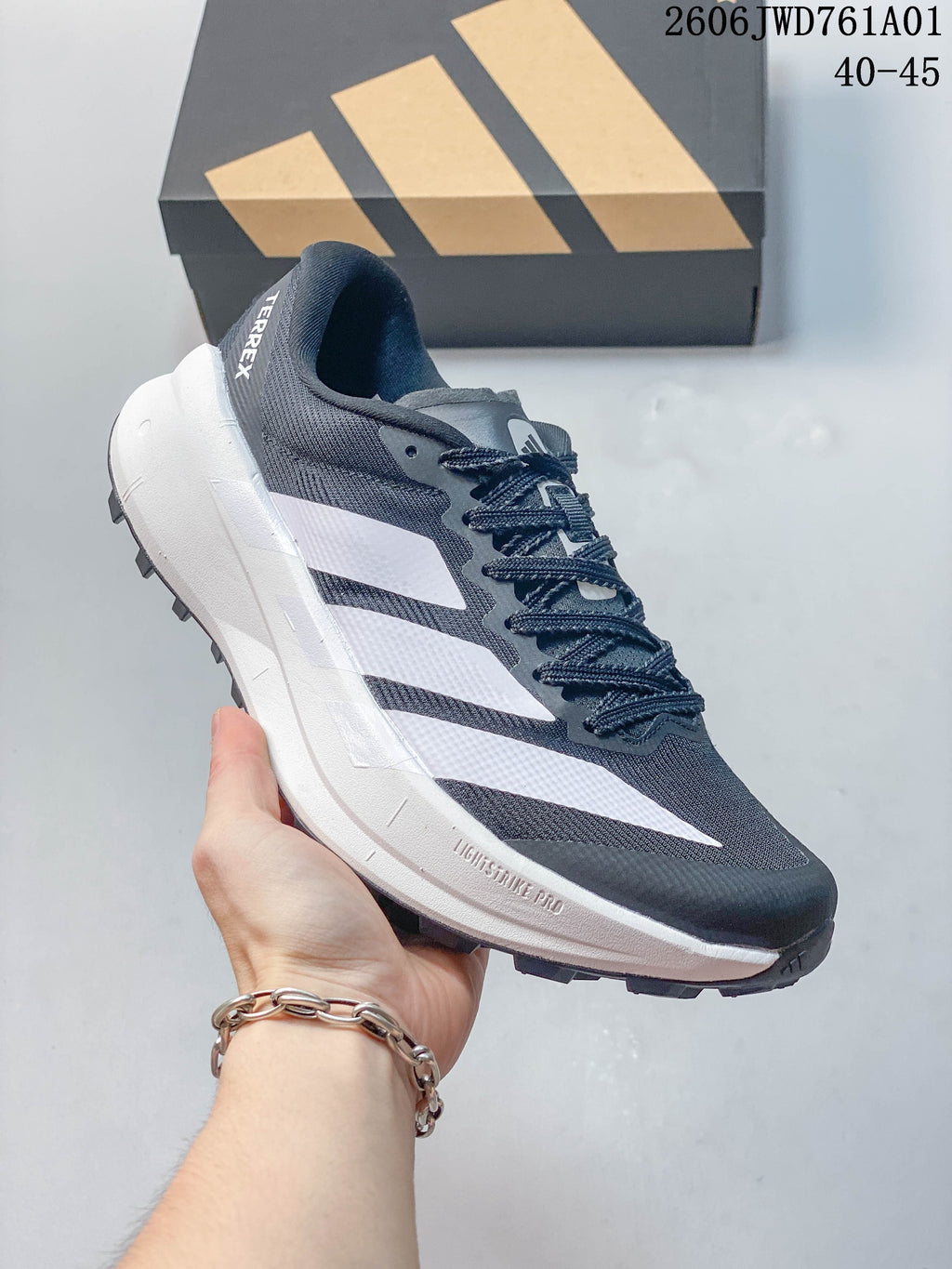 Dark gray Adidas Terrex trail running shoe with white stripes, shown from the side