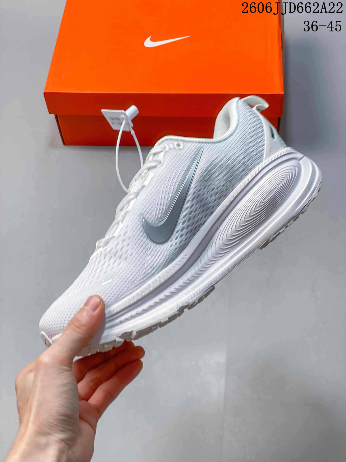 Side view of a white running shoe with a metallic-look Swoosh and sculpted sole