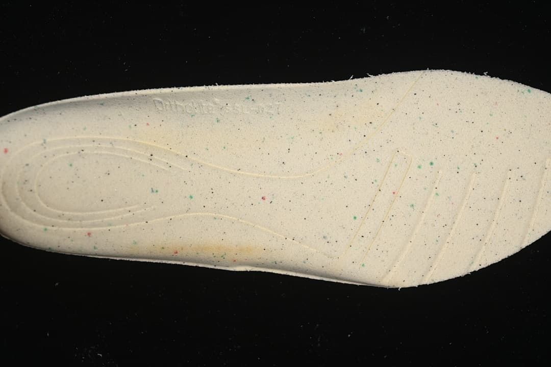 Close-up of a light-colored shoe insole with scattered colored speckles.