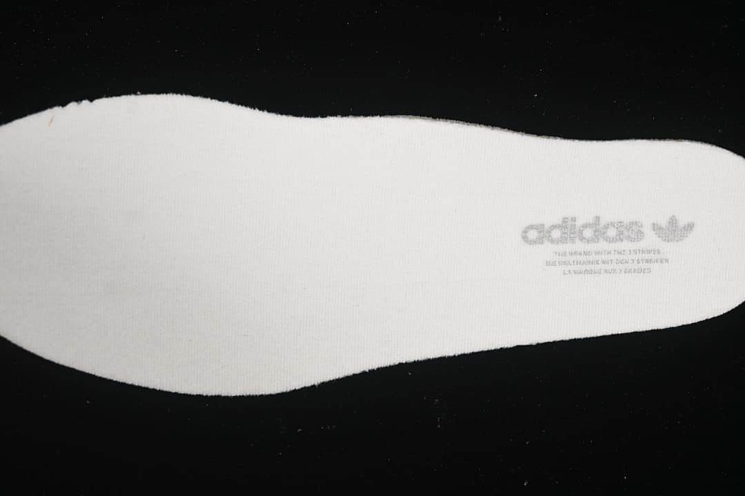 Reverse side of a light-colored shoe insert with adidas branding
