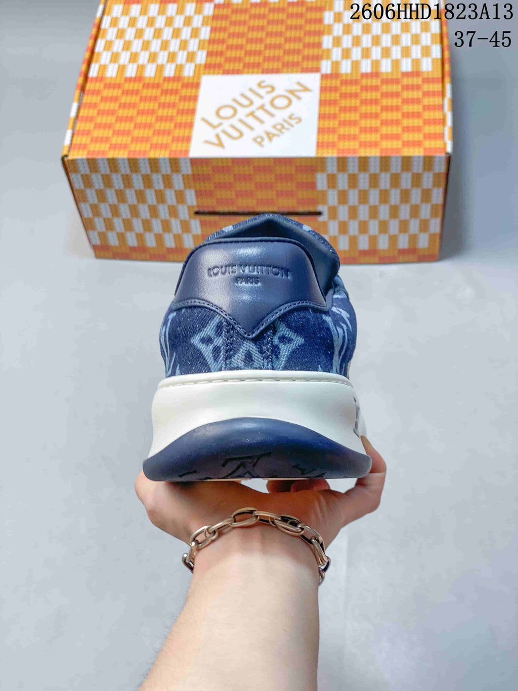 Rear view of a blue patterned low-top sneaker with a dark blue heel panel and two-tone sole.