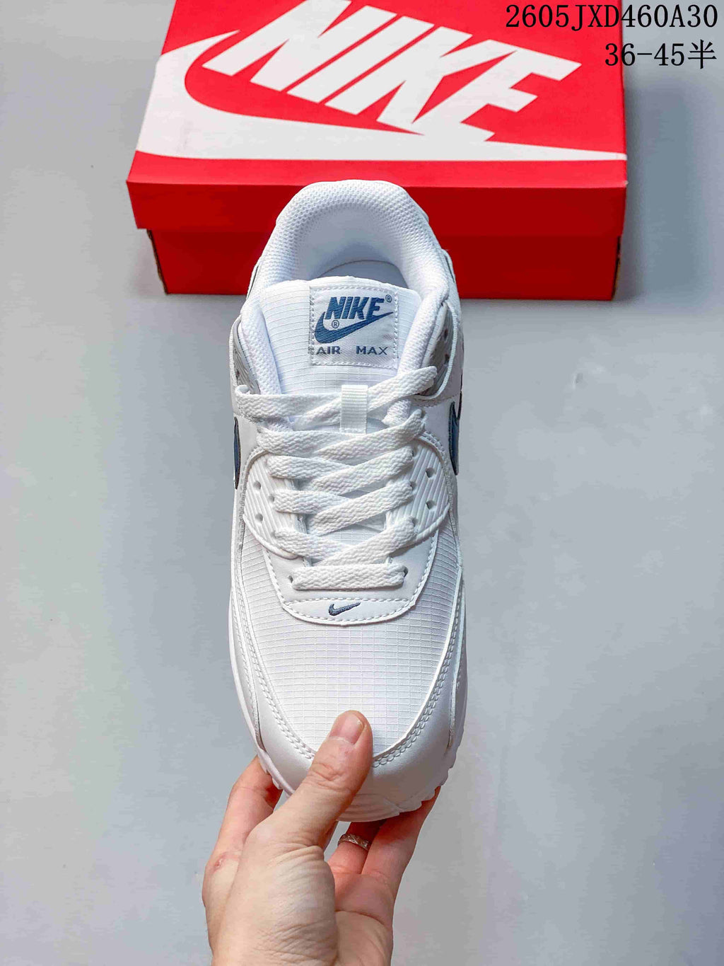 Top view of a white Nike Air Max 90 sneaker with blue tongue branding