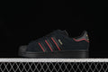 Side view of a black adidas Superstar-style sneaker with red accents and gold details