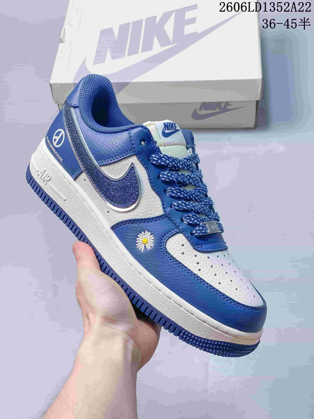 Blue and white low-top sneaker with patterned laces, glitter-effect Swoosh and daisy embroidery.