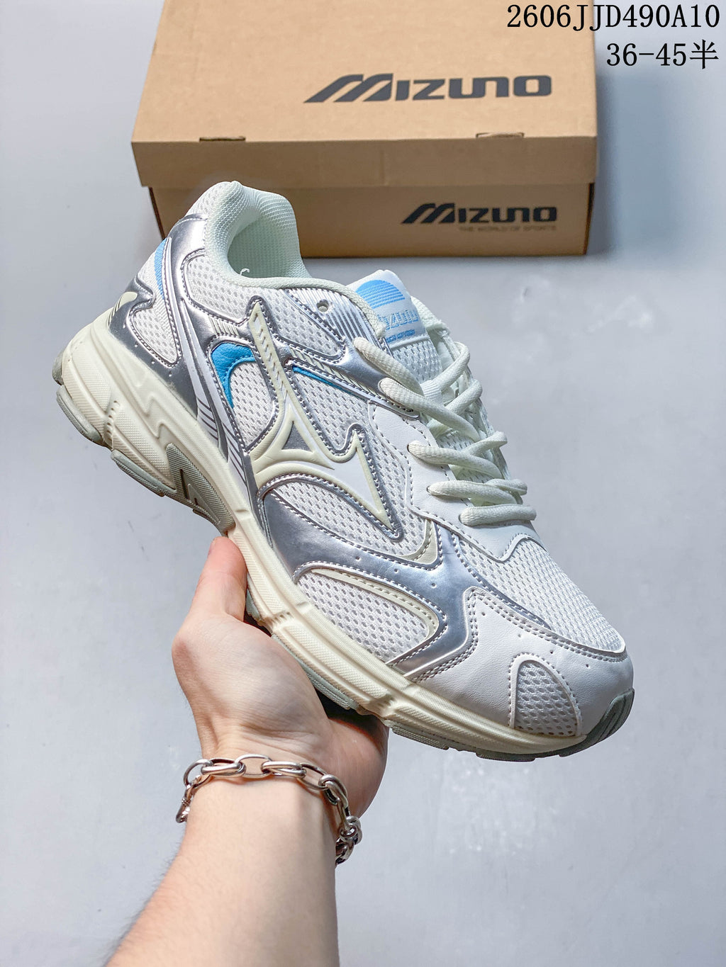 Silver and white mesh Mizuno sneaker with blue details and a cream-colored sole.