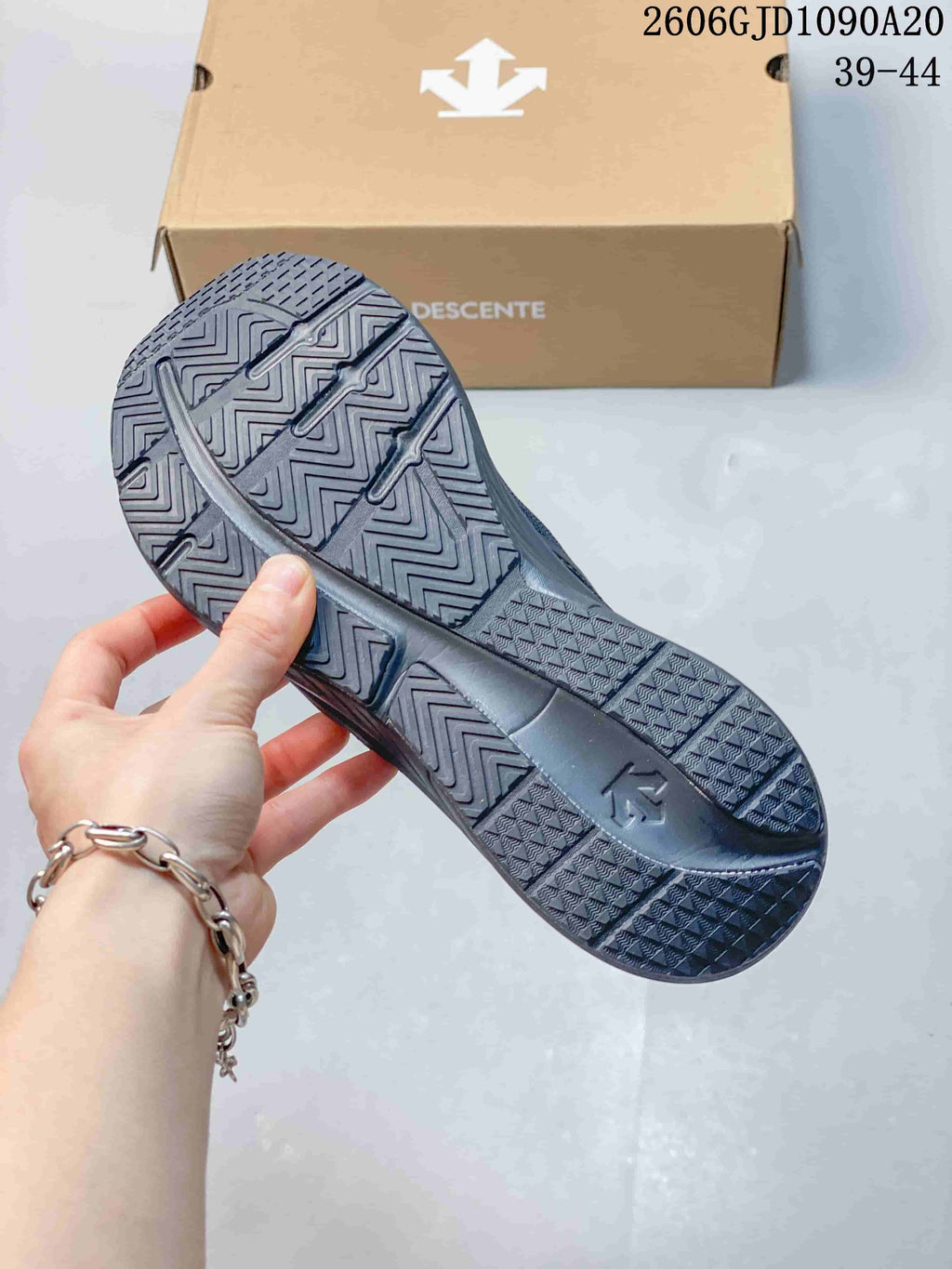 Geometric tread pattern on the outsole of a dark gray Descente shoe