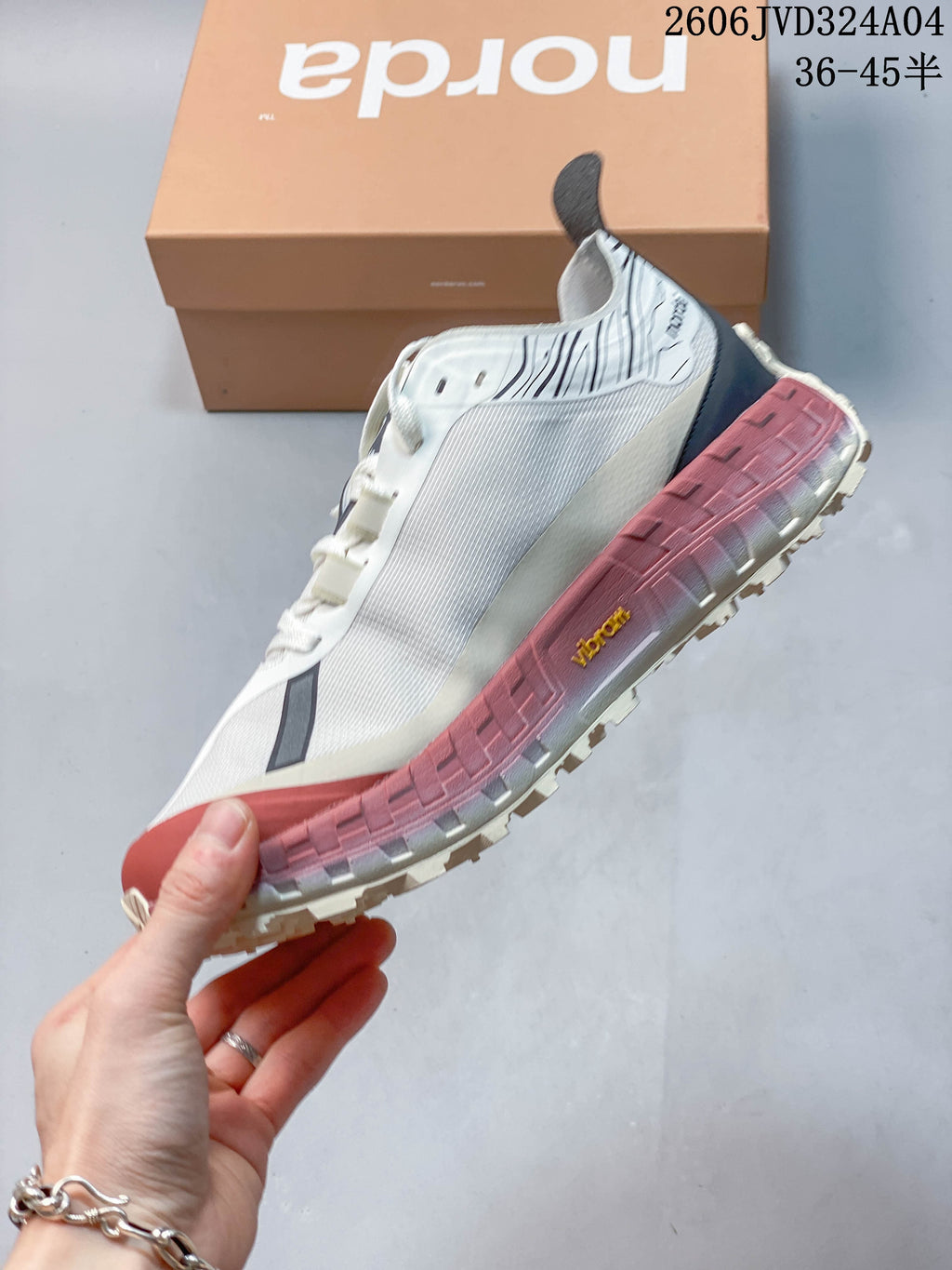 Side view of a white Norda sneaker with dark accents and a rose-colored sole.