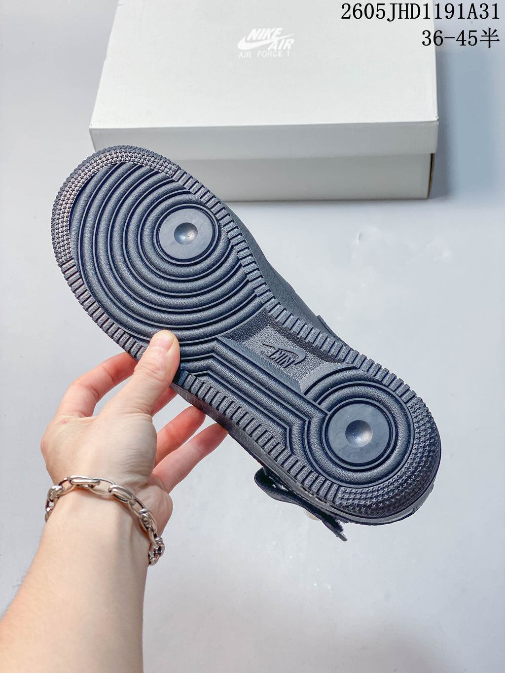 Underside of a gray sneaker showing a circular-pattern rubber outsole
