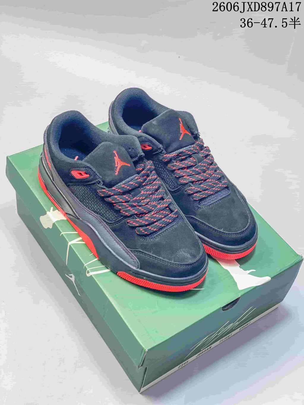 Pair of dark Jordan Flight Court low-top shoes with red accents on a green shoebox