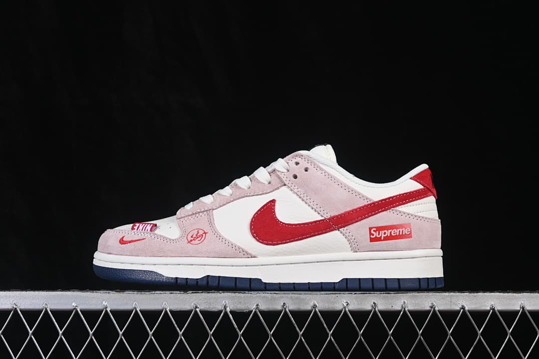 Side view of a white, pale pink, and red low-top Nike SB Dunk sneaker