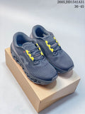 Pair of charcoal gray On Cloudmonster 3 running shoes with yellow lace accents, shown on a box.