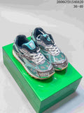 Pair of turquoise, black, and silver Bottega Veneta Orbit lace-up runner sneakers on a green box