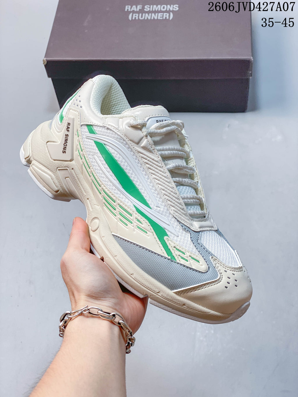 Side view of the cream sneaker with green accents and layered upper details