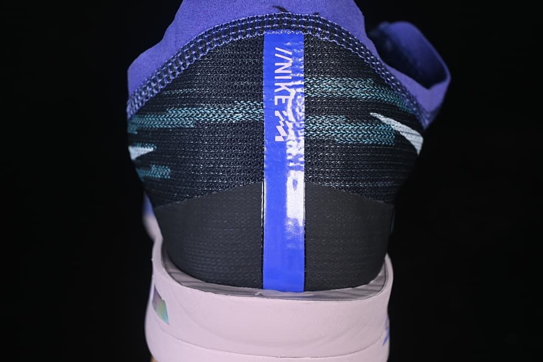Rear view of the shoe showing the heel and violet pull tab.