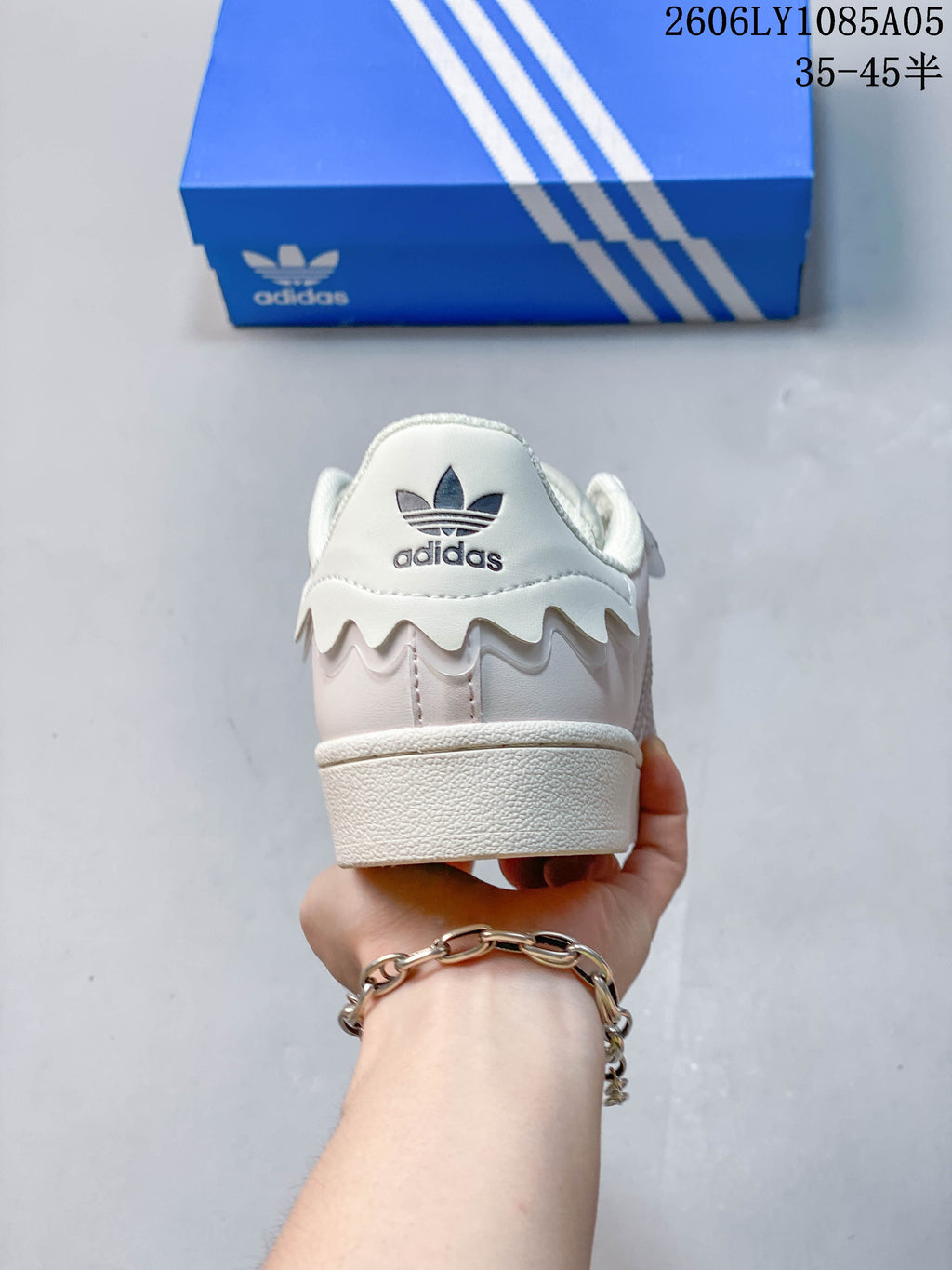Heel view of the off-white sneaker with a wavy overlay and Adidas trefoil branding.