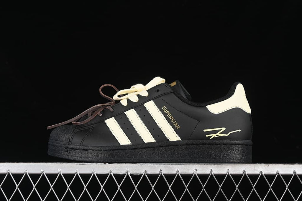 Side view of the black and cream Superstar sneaker with contrasting laces.