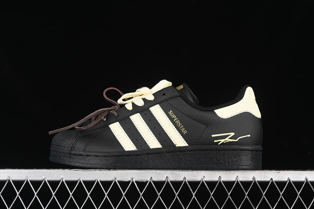 Side view of the black and cream Superstar sneaker with contrasting laces.