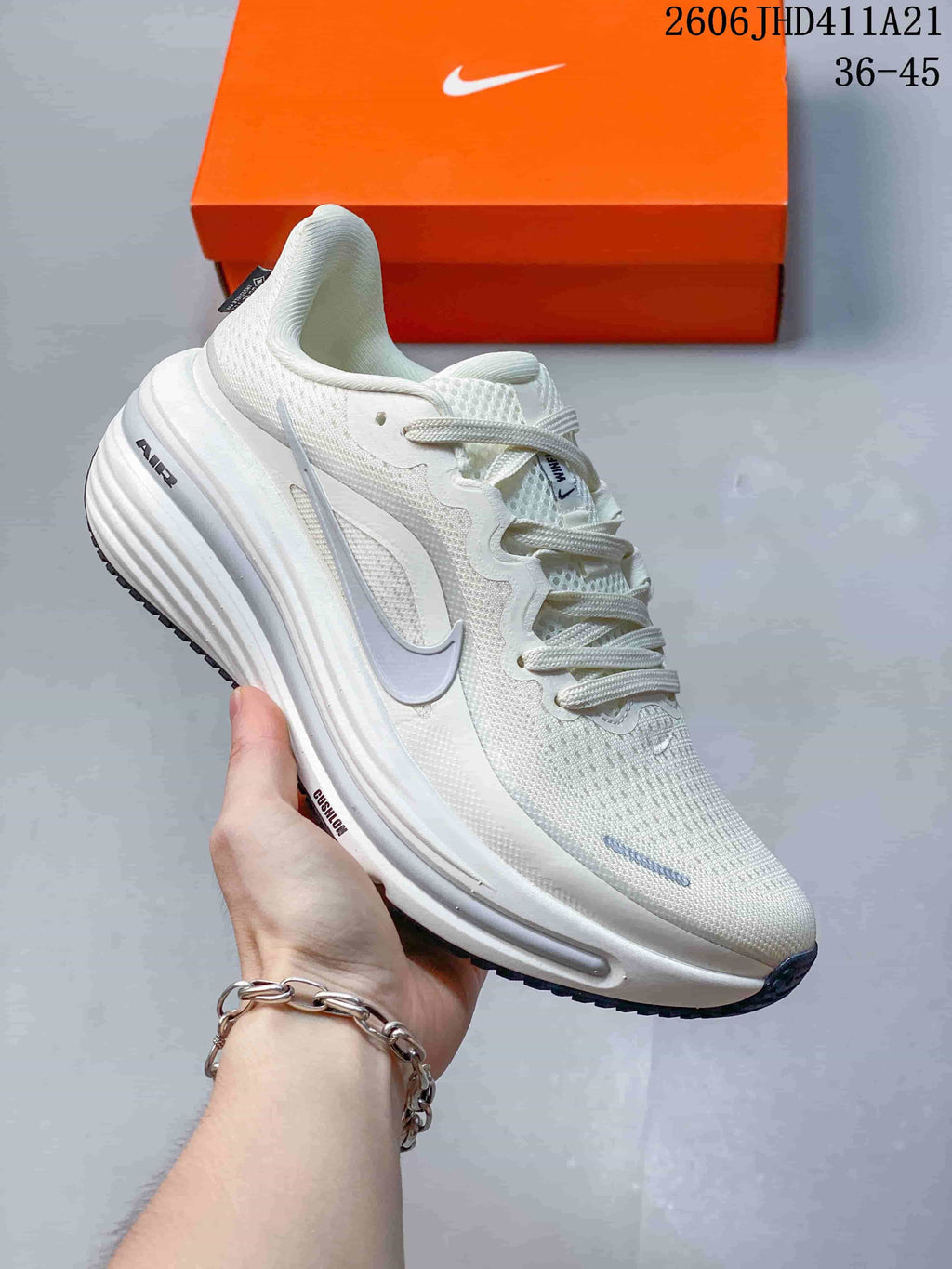 White Nike Air Zoom Winflo 12 shoe with grey details beside an orange shoe box