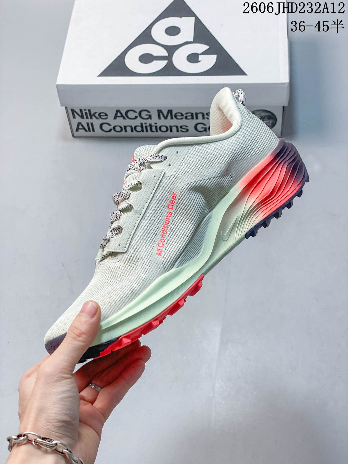 Side view of the pale Nike ACG Pegasus Trail shoe with dark swoosh, coral details, and lugged outsole.