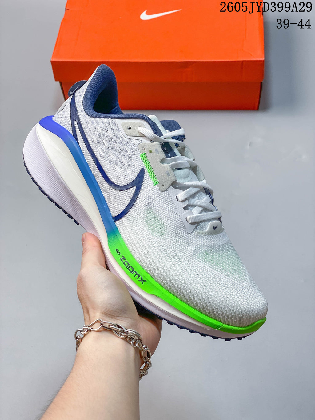 White and light gray Nike Air Zoom Vomero 17 running shoe with blue and bright green accents.