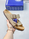 Beige two-strap sandal with adjustable buckles and contoured footbed, shown beside a blue shoe box.