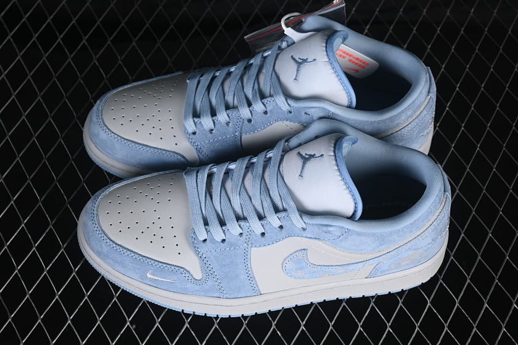 Pair of pale blue and white low-top sneakers viewed from above, showing perforated toe panels, laces, and Jordan tongue logos.