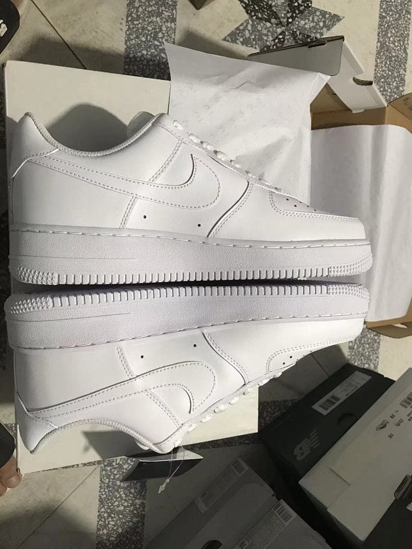 Side view of the white sneakers resting on a shoe box.