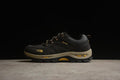 Side view of a black The North Face hiking shoe with yellow details and a beige midsole.