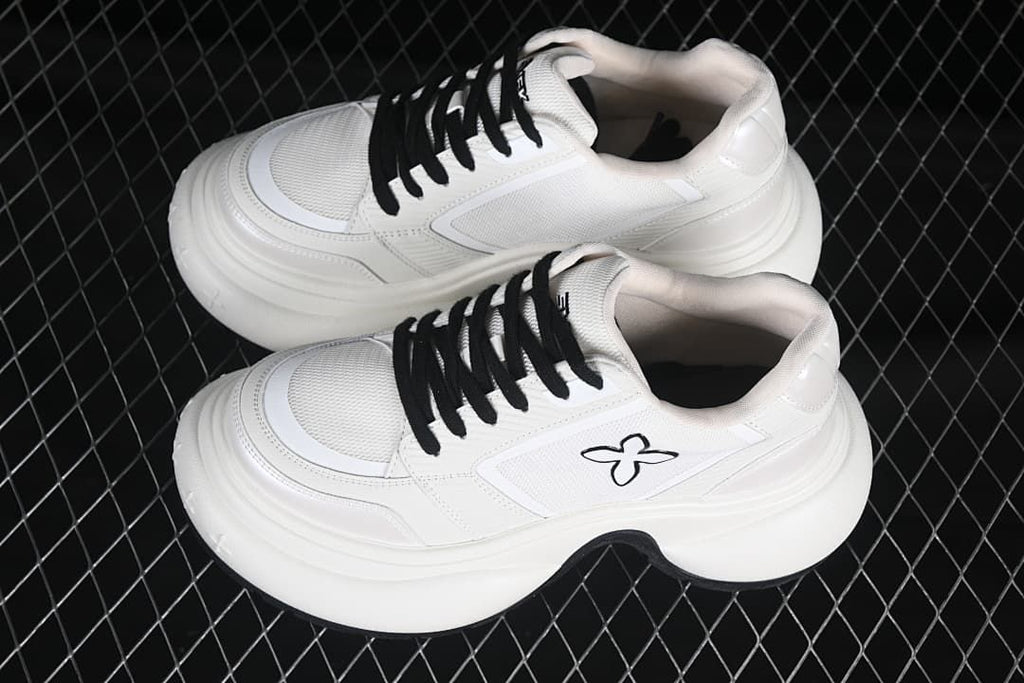 Pair of white low-top sneakers with black laces and sculpted soles
