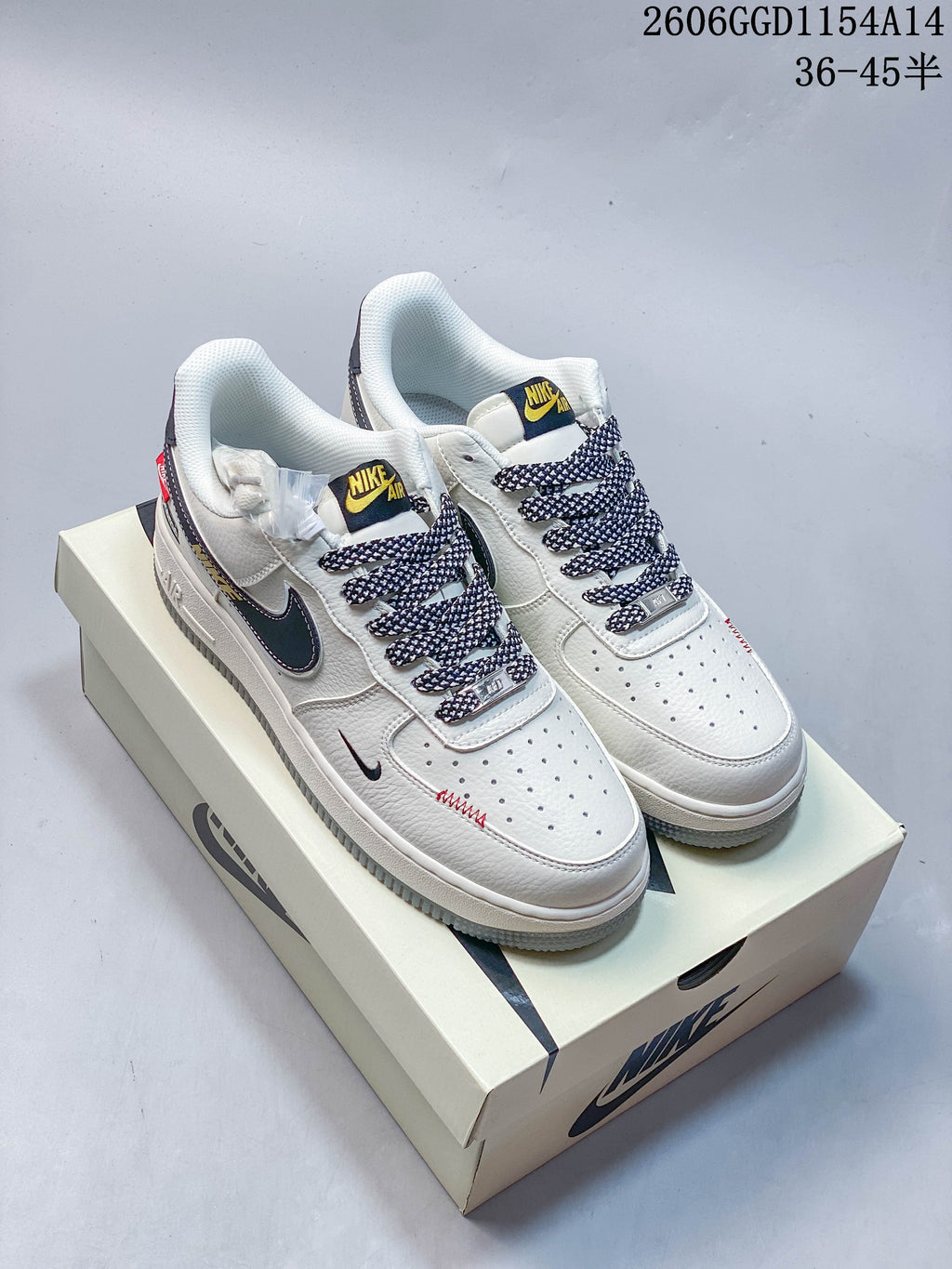 Pair of off-white low-top sneakers with patterned laces, dark swooshes and contrasting tongue labels.