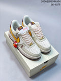 Pair of ivory and gold low-top sneakers with burgundy accents and a red hanging figure accessory