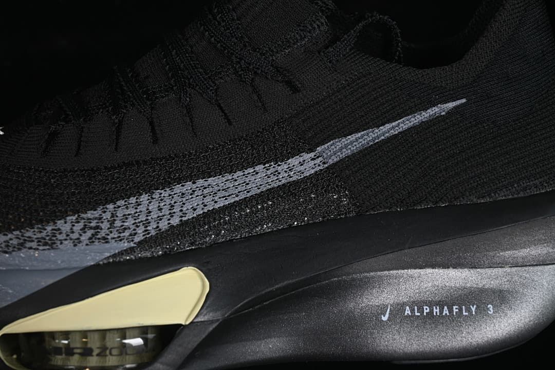 Close-up of silver Swoosh, black upper, and Alphafly 3 sole marking