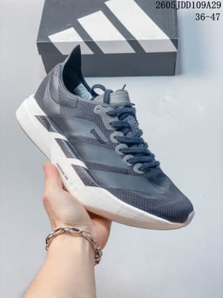 Grey and navy Adidas running sneaker held in front of an Adidas shoebox.