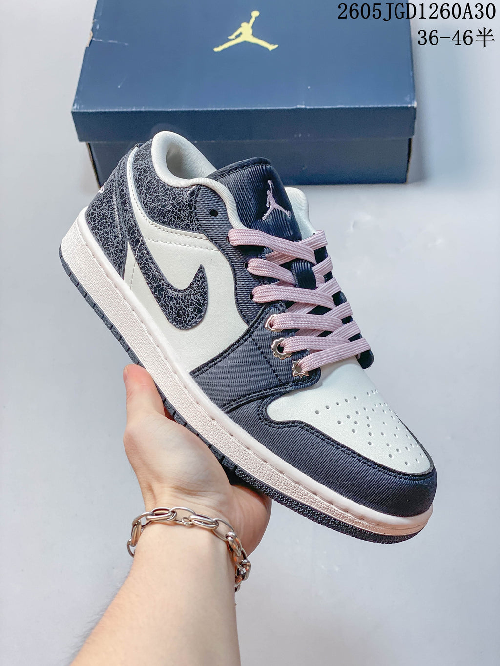 Angled view of a navy and white Jordan low-top sneaker with pink accents