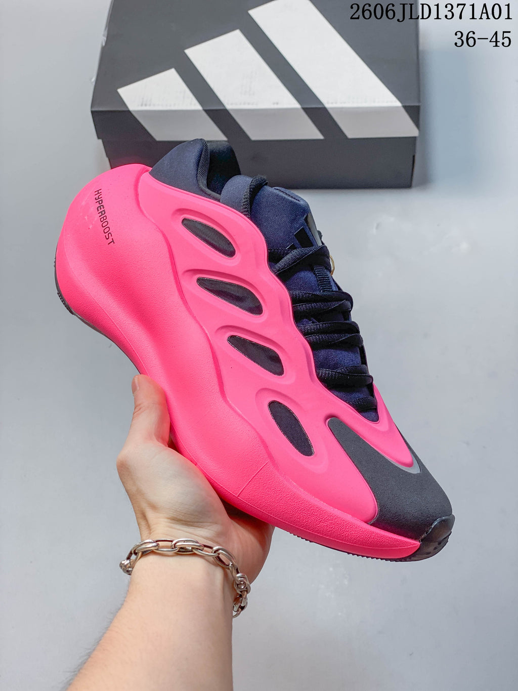 Angled side view of a pink, navy, and charcoal Adidas Hyperboost sneaker.