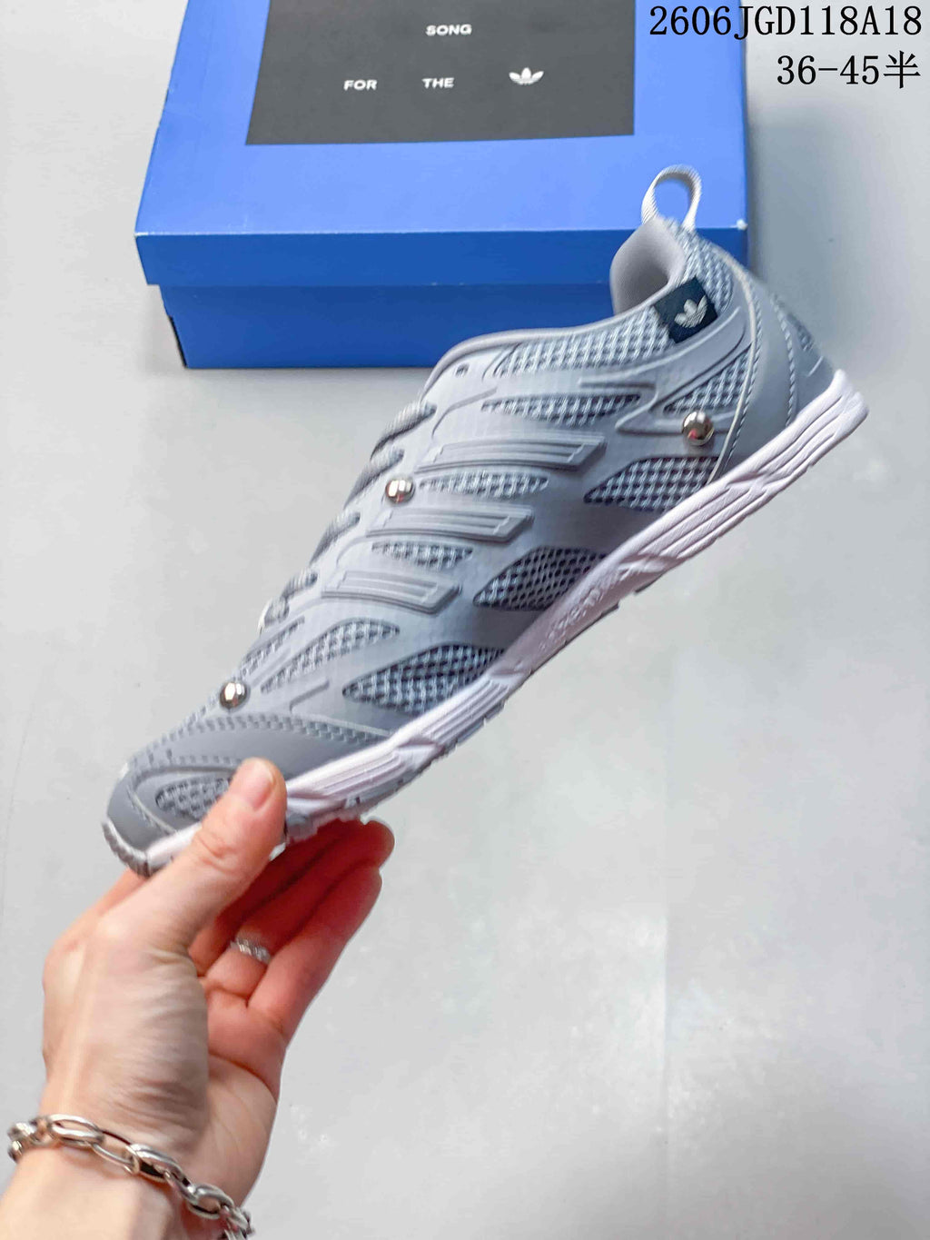 Side view of a grey sneaker with three-stripe detailing and mesh panels