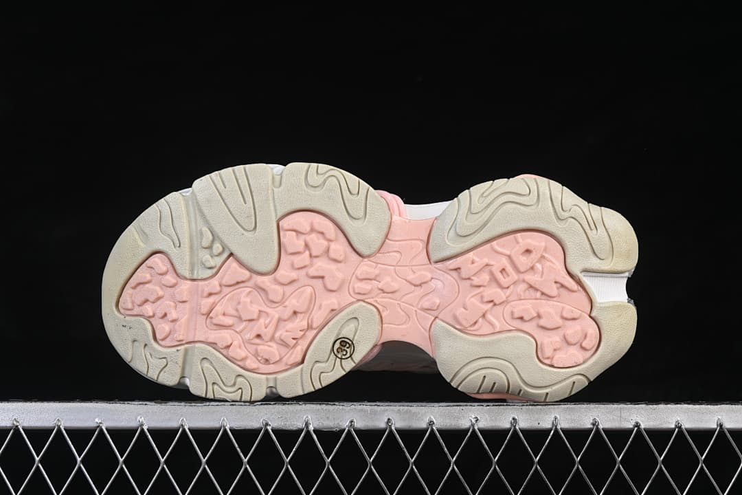Underside of the sneakers showing a pale pink and beige patterned outsole.