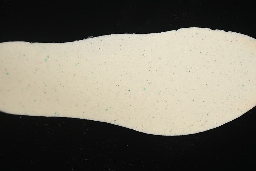 Close-up of a light-colored shoe insole with small colored specks
