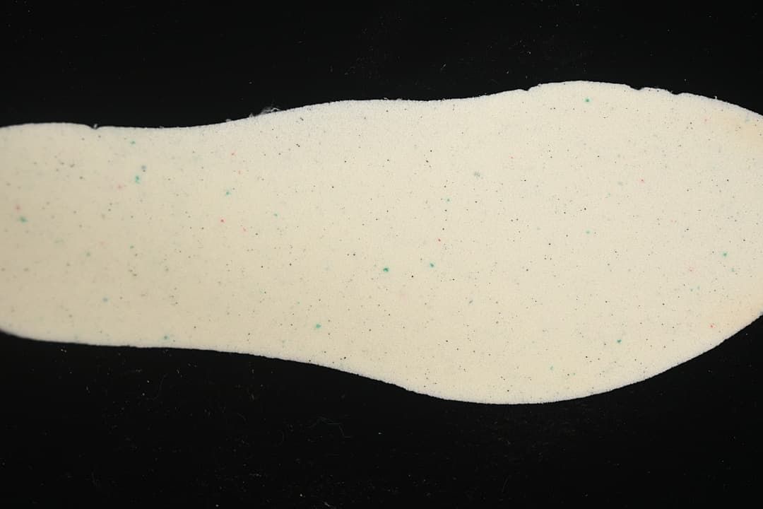 Close-up of a light-colored shoe insole with small colored specks