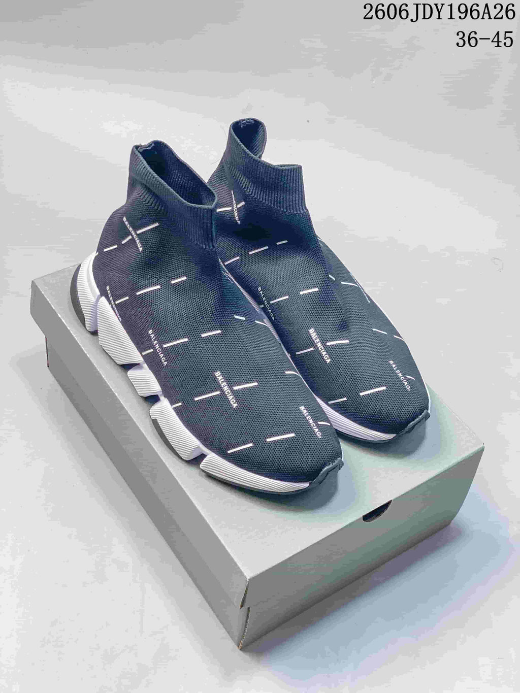 Pair of dark gray sock-style sneakers with small branding marks and white segmented soles.