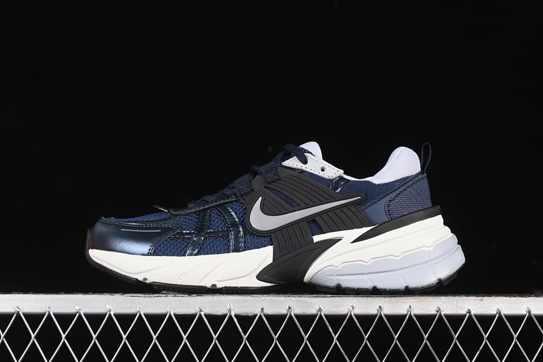 Side view of navy Nike V2K Run sneakers with black and white details