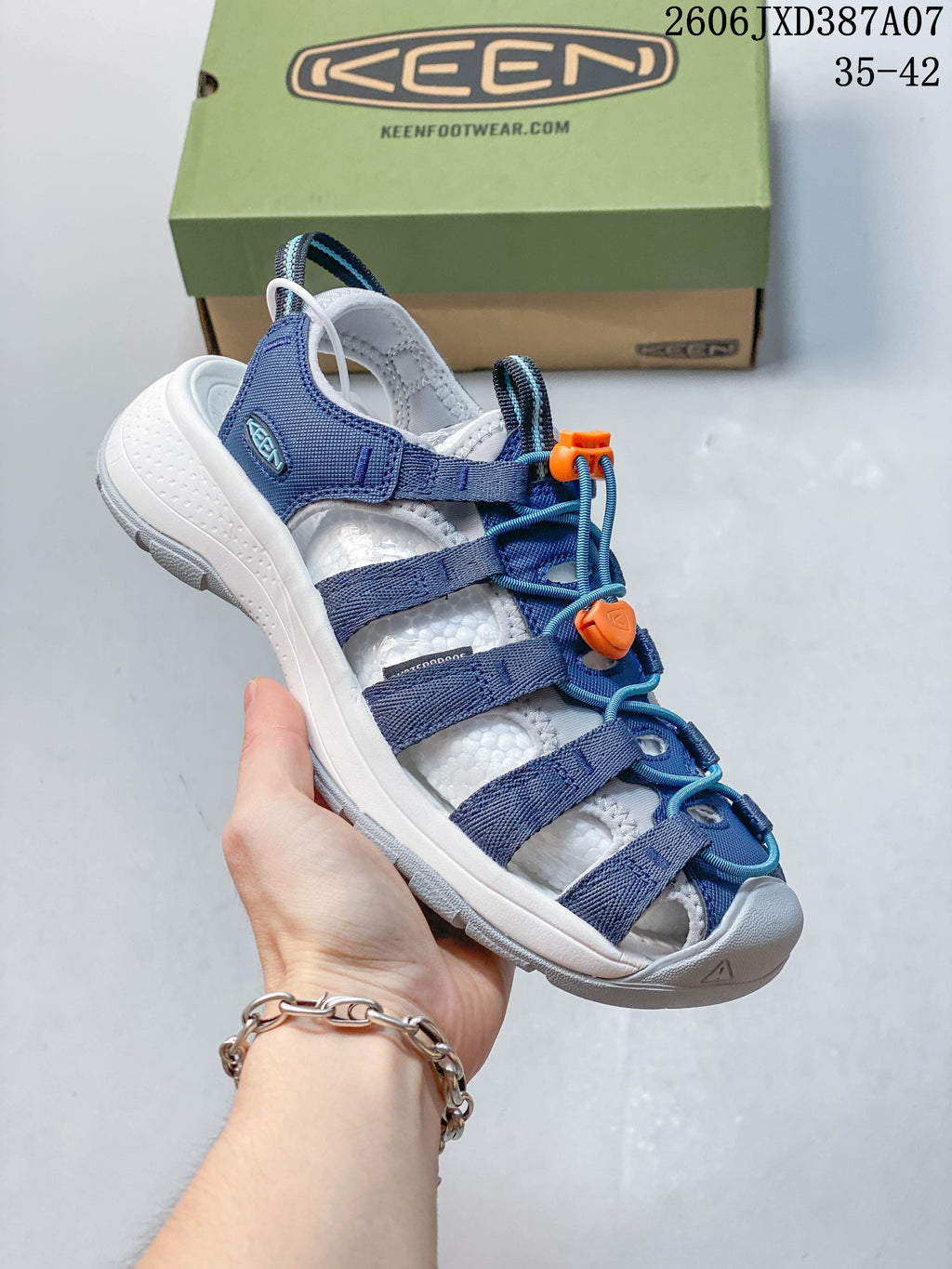 Angled view of the sandal highlighting its blue straps and orange lace toggles