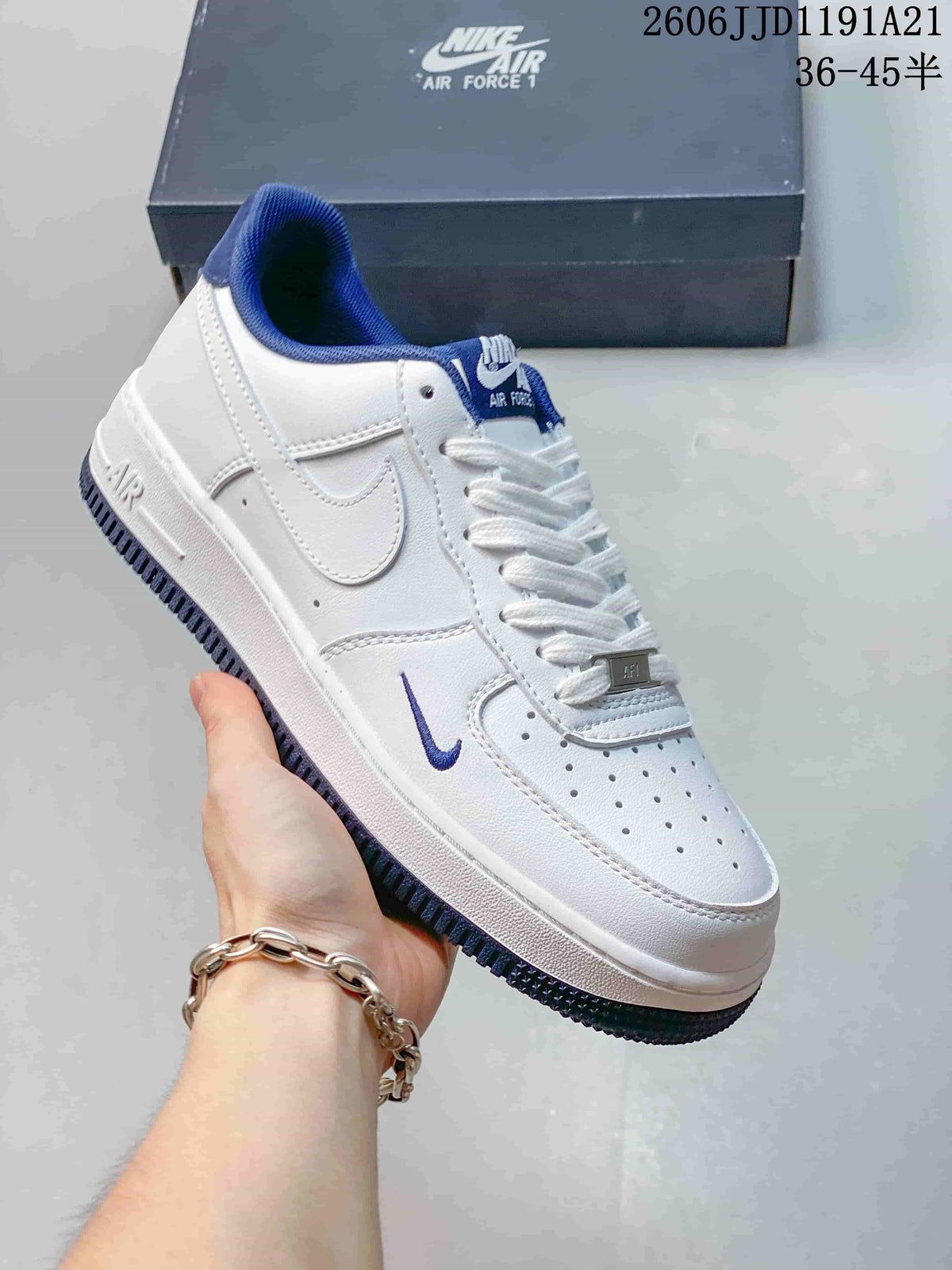 Close-up of a white low-top sneaker with blue lining, a small blue Swoosh, and a perforated toe.