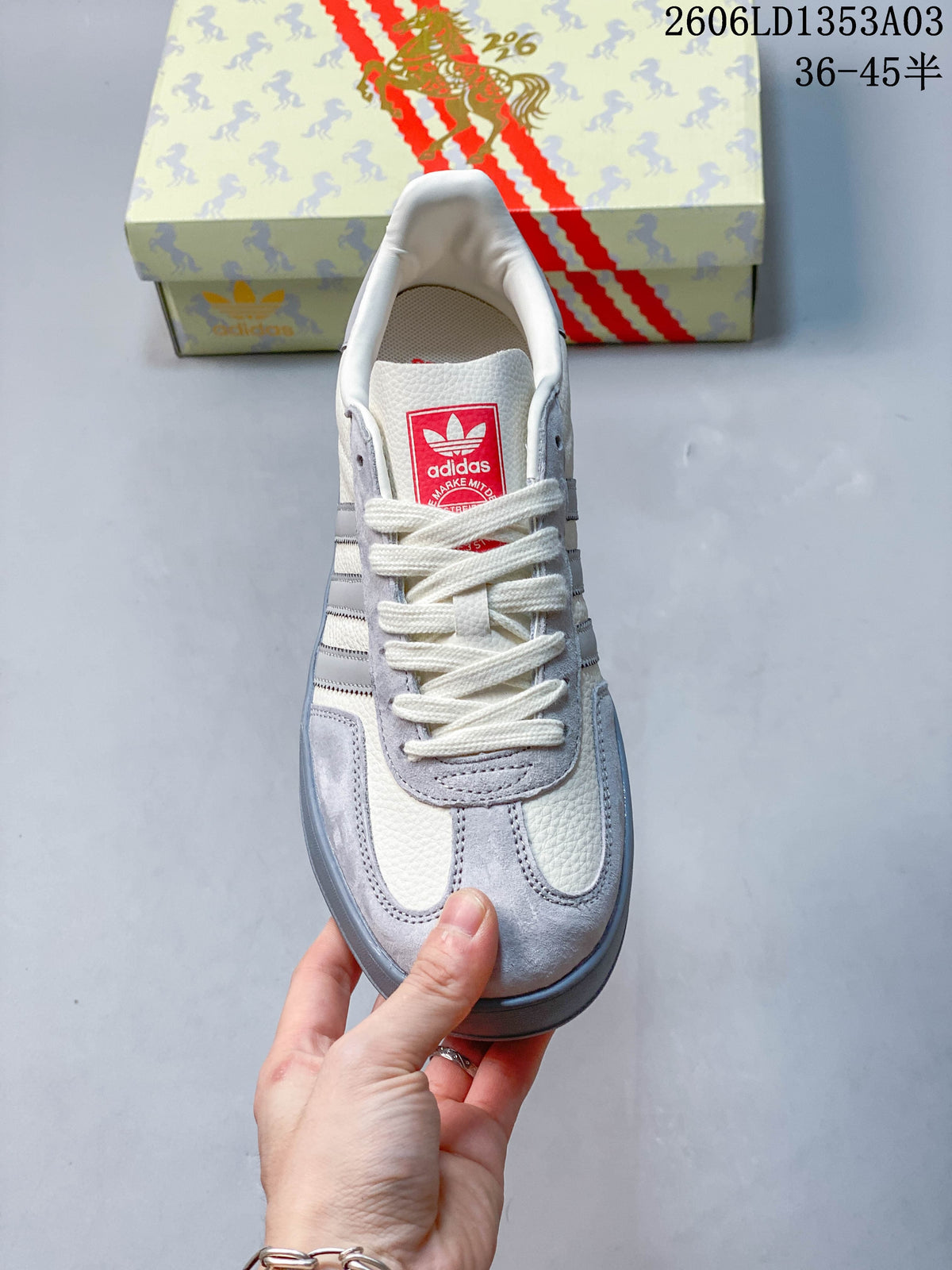 Top view of a white and grey lace-up sneaker with red tongue label