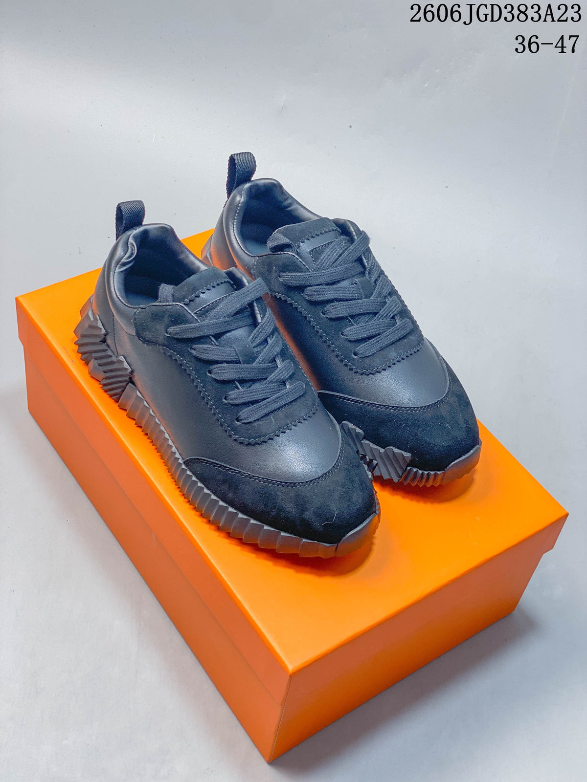 Pair of dark navy low-top lace-up sneakers with textured panels and ridged soles on an orange box.