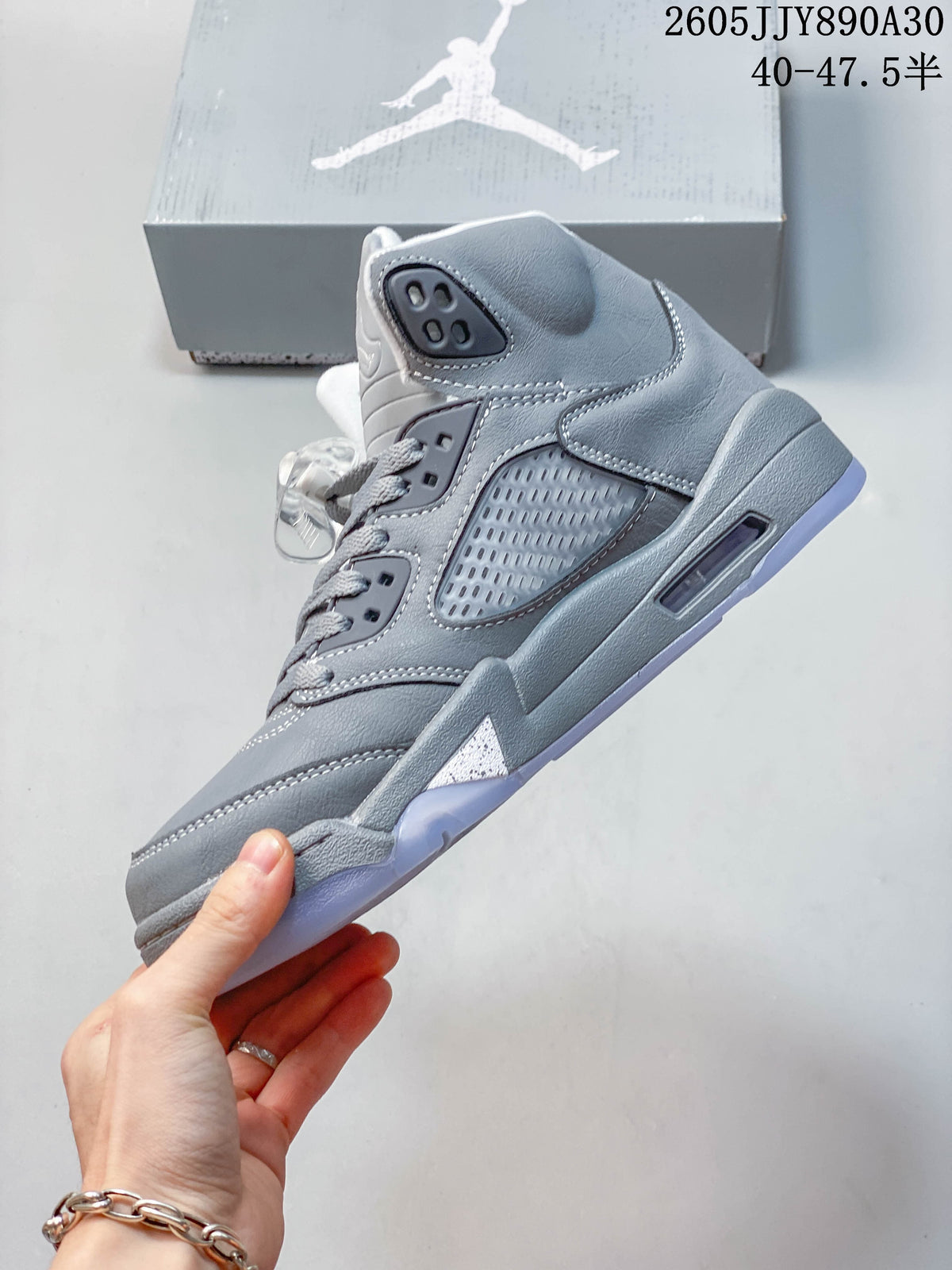 Side view of a grey Jordan Air Jordan 5 Retro high-top sneaker showing mesh panels and cushioning window