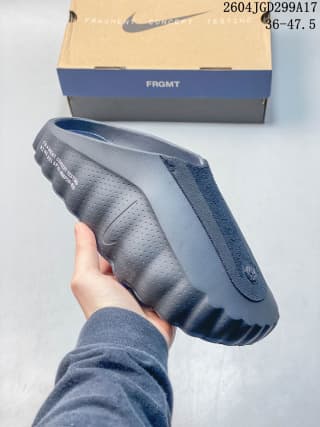 Close side view of a dark Nike Mind slide with a textured upper and segmented outsole.