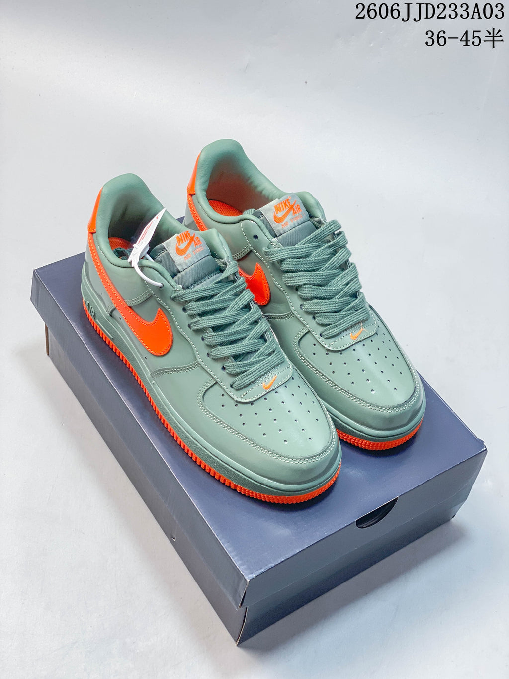 Pair of green Nike Air Force 1 ’07 low-top sneakers with bright orange accents on a shoebox